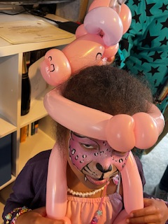 girl with pink unicorn balloon and face painted in Stafford